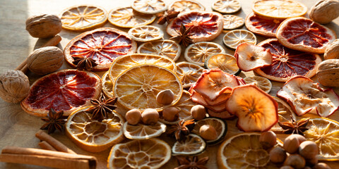 Dried citrus fruits and apple rings with nuts on rustic wood for the christmas. Preparations for christmas hot drinks.