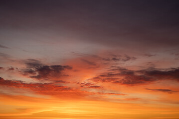 Fototapeta premium Vibrant sky displaying a stunning gradient of reds, oranges, and yellows with dramatic clouds during a colorful sunset, illustrating natural beauty and twilight atmosphere