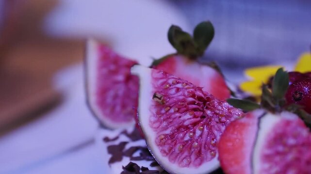 D&eacute;tail d&rsquo;un dessert de mariage avec figues, fraises, copeaux de chocolat et fleurs comestibles sous lumi&egrave;re bleue, ambiance &eacute;l&eacute;gante et festive.