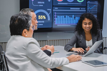 Diverse business team analyzing financial data and performance metrics during a corporate meeting....