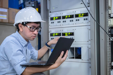 Electrical engineer male checking voltage at the Power Distribution Cabinet in the control room,preventive maintenance Yearly,inspecting power system and control panel in industrial factory