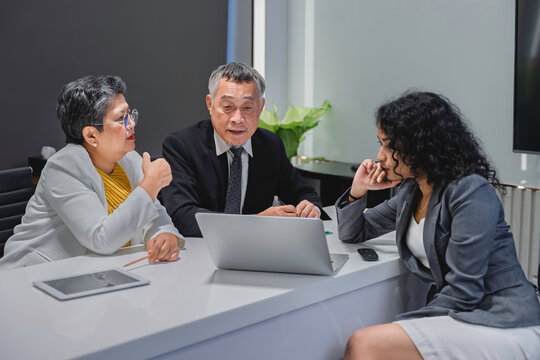 Diverse business team analyzing financial data and performance metrics during a corporate meeting. Professional teamwork, strategy planning, and data-driven decision making in modern office.