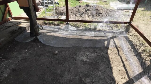 A male worker casually laying metal net on the ground with his feet.
