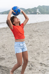 Happy girl playing with soccer ball on beach