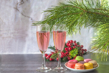 Two glasses of pink champagne, plate with macaroons and christmas decoration