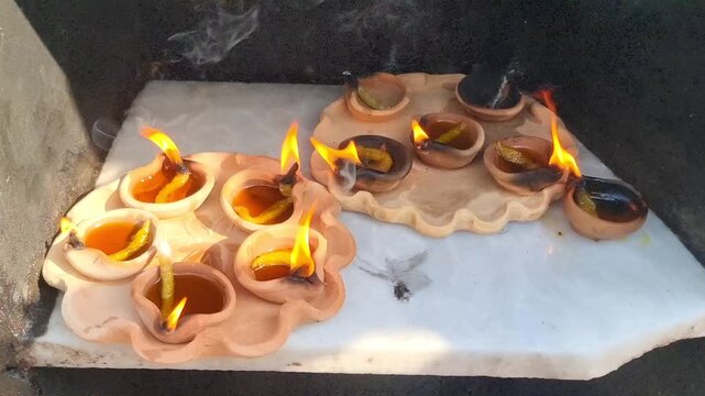 Diya or deepak are burning at a shrine in Pakistan. People light lamps at shrines to make offerings. Lighting a diya in a temple is an offering by a devotee to God in india. Slow Motion 4K Footage.