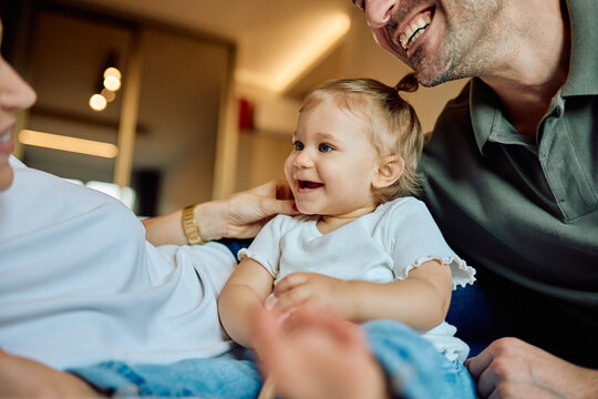 Cheerful baby girl laughing and interacting with her parents, enjoying family togetherness, love, and childhood joy indoors