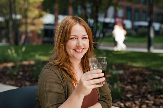 Plus size woman drinking soft soda drink with her lunch.