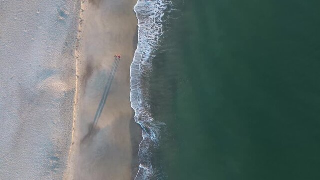 Aerial view of a couple walking on the beach in Oak Island NC at sunrise