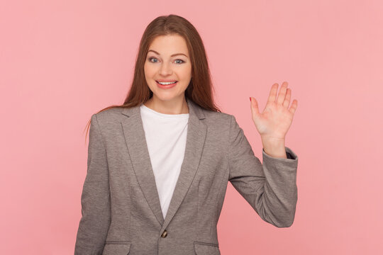 Friendly smiling woman waving hand, saying hello or good bye, expressing positive emotions