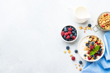 Yogurt with fresh berries and granola on white table.