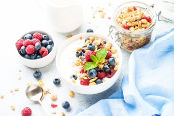 Yogurt with fresh berries and granola on white table.