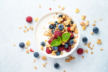 Yogurt with fresh berries and granola on white table.