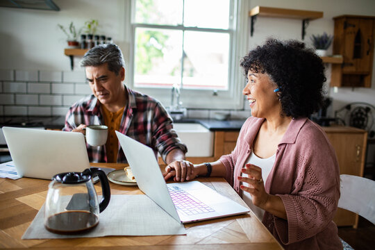 Smiling mature couple working from home in kitchen