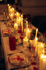 Warm candlelit banquet table with roses and crystal decor in restaurant