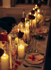 Warm candlelit banquet table with roses and crystal decor in restaurant