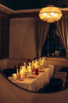 Warm candlelit banquet table with roses and crystal decor in restaurant
