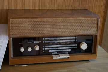 Vintage wooden radio on a wooden table with knobs and dials visible in a retro setting