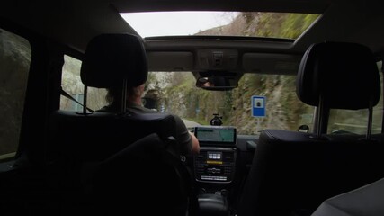 Man drives modern SUV through curvy rugged canyon road, embarking on a thrilling outdoor exploration journey in alpine scenery