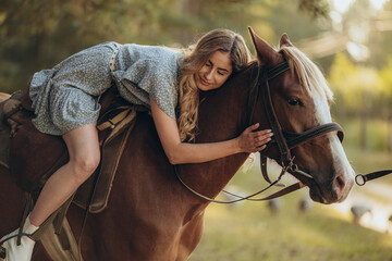 Obraz premium A young beautiful woman rides a horse in the forest in autumn. Horseback riding in the evening in autumn.