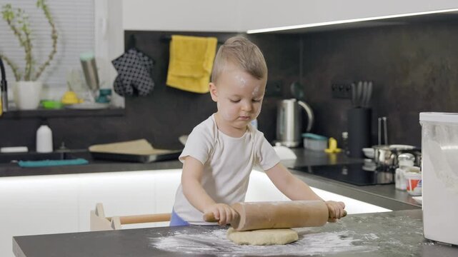 Toddler boy learning baking with rolling pin