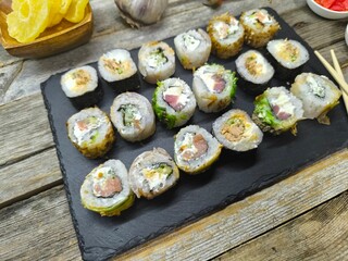 Close-up of various sushi lying on granite board next to wooden chopsticks