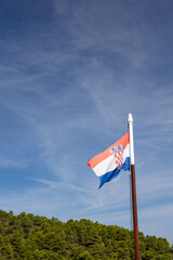 Croatian National Flag Flapping in Wind Over Clear Sky and Green Hills