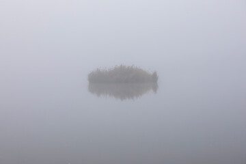Landscape of a misty lake with a small island in the water