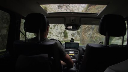 Man driving an off road vehicle through a narrow mountain gorge. Dangerous road trip adventure with beautiful panoramic view from the car - Powered by Adobe