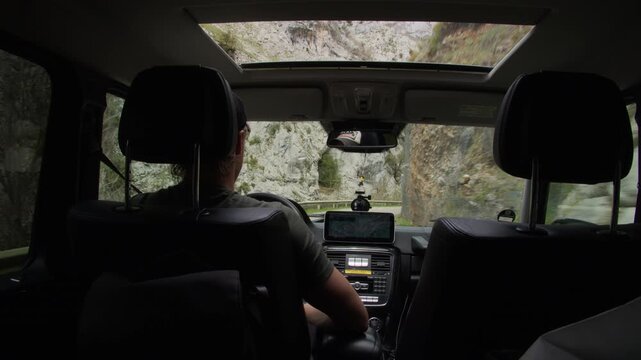 Man driving an off road vehicle through a narrow mountain gorge. Dangerous road trip adventure with beautiful panoramic view from the car