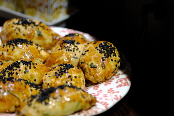 Macro and close-up shot of delicious homemade black cumin pastries. Turkish pastries. Breakfast pastries with cheese and parsley, made by a housewife, on a red plate. Traditional delicacies.