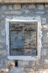 Weathered Wooden Door Shutters Set in a Cracked Stone Wall, Creating a Rustic Vintage Exterior