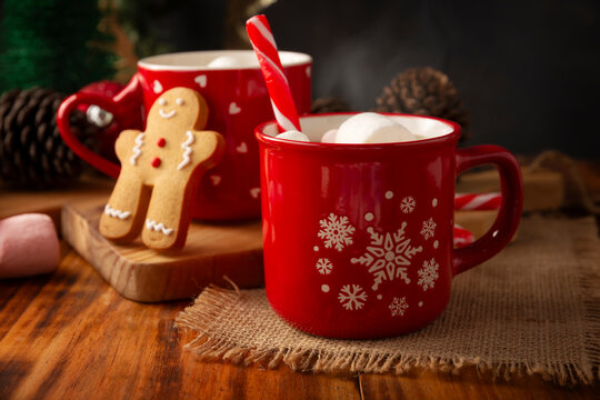 Hot chocolate with marshmallows, a traditional hot drink made for Christmas time and holidays. Served in a red mug and accompanied by gingerbread men cookies.