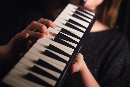 Woman playing melodica. Kid practicing music. Musical instrument for learning. Close up on hands on keyboard of harmonicas for performance.