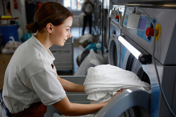 Fototapeta premium A woman wearing a white shirt is diligently working in a laundromat