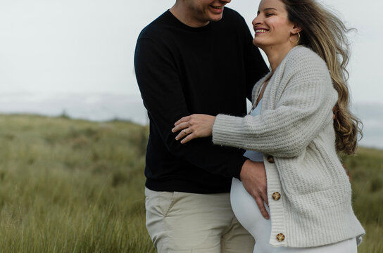 casal jovem apaixonado e feliz, mulher gr&aacute;vida rindo com o seu marido
