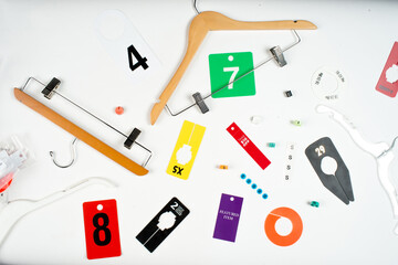 Flat lay of assorted clothing hangers, size markers, and retail tags arranged on a white background. Concept for fashion merchandising, inventory management, and retail display systems.