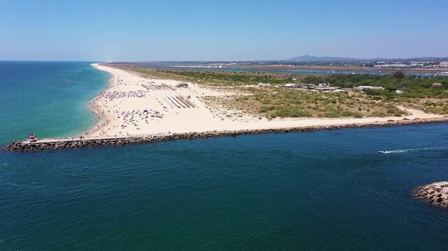 Aerial view drone shot of Tavira Portugal Algarve sunny crowded beach with umbrellas and turquoise sea on tavira sandspit lifeguard watch and families enjoying waves, beach umbrellas,