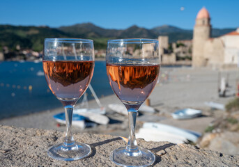 Glasses of rose Collioure AOC wine in sunlights with view on old town Collioure, colorful houses,...