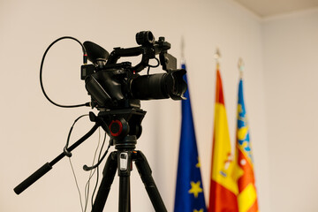 Video camera filming political press conference with flags