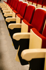 Empty auditorium hall with red chairs and beige armrests