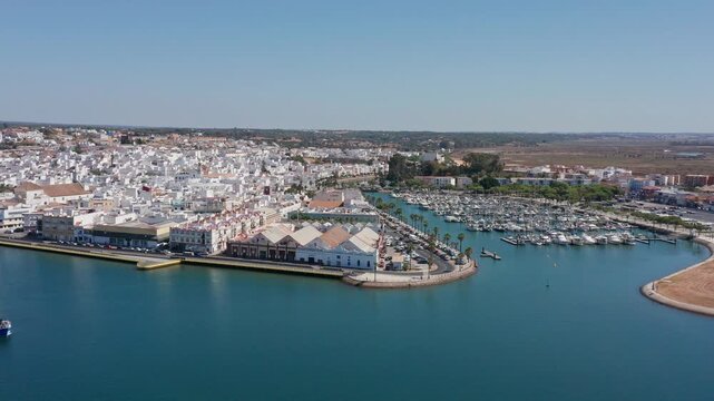 Aerial view drone shot of Ayamonte aerial view ayamonte marina whitewashed town calm Guadiana River moored boats and yachts narrow harbor channels sandy spit sunlit rooftops winding streets