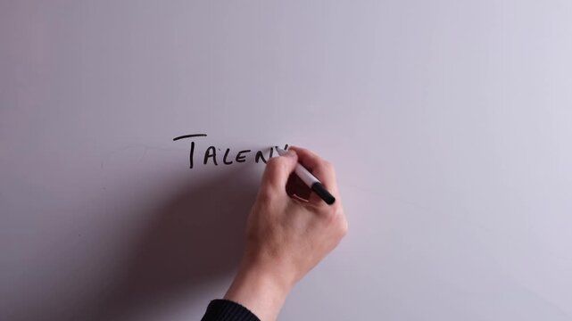 An HR business professional is writing Talent Acquisition on a whiteboard in black marker pen, ideal for HR, recruitment, and business workplace presentations.