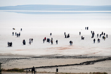 The salt lake in Ankara, Turkey fascinates visitors with its white salt cover. The photo shows many visitors walking on the salt lake.