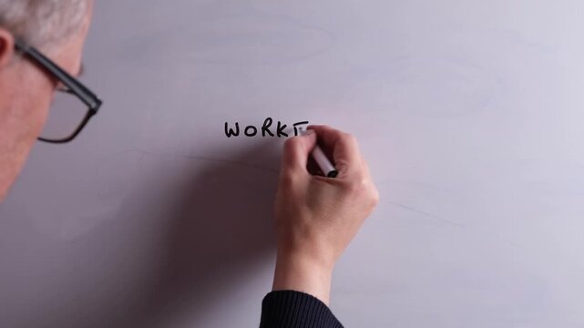 An HR business professional is writing Workforce Planning on a whiteboard in black marker pen, ideal for HR, recruitment, and business workplace presentations.