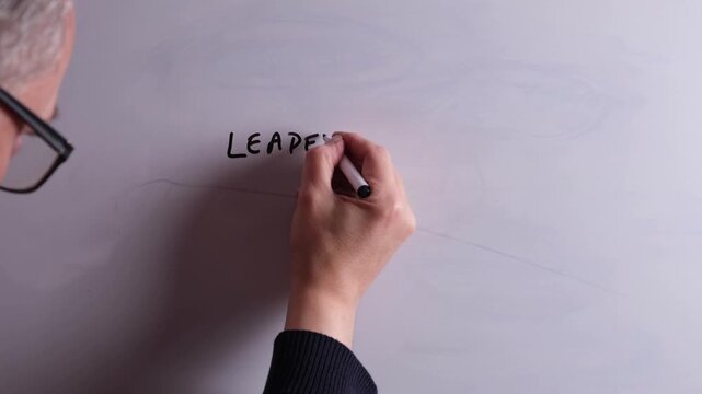 An HR business professional is writing Leadership Development on a whiteboard in black marker pen, ideal for HR, recruitment, and business workplace presentations.