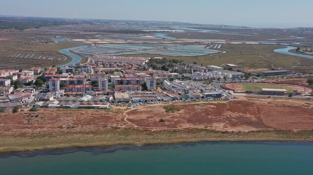 Aerial view drone shot of Ayamonte Aerial view Ayamonte coastline and river marshes winding Guadiana channel with salt pans, red cliffs, calm turquoise water and distant farmland.