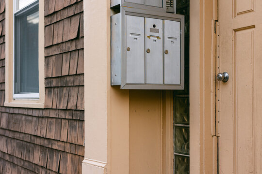 Mailboxes mounted on a wall near an entry door of a residential building with rustic wood siding