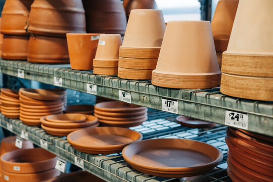 Various clay pots and dishes displayed on shelves in a garden center during daylight hours