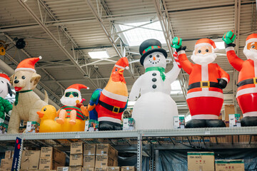 Holiday decorations displayed on shelves in a store featuring inflatable Santa figures and a snowman
